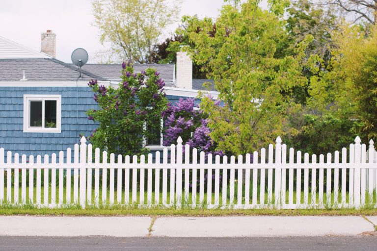 a white picket fence in front of a blue house