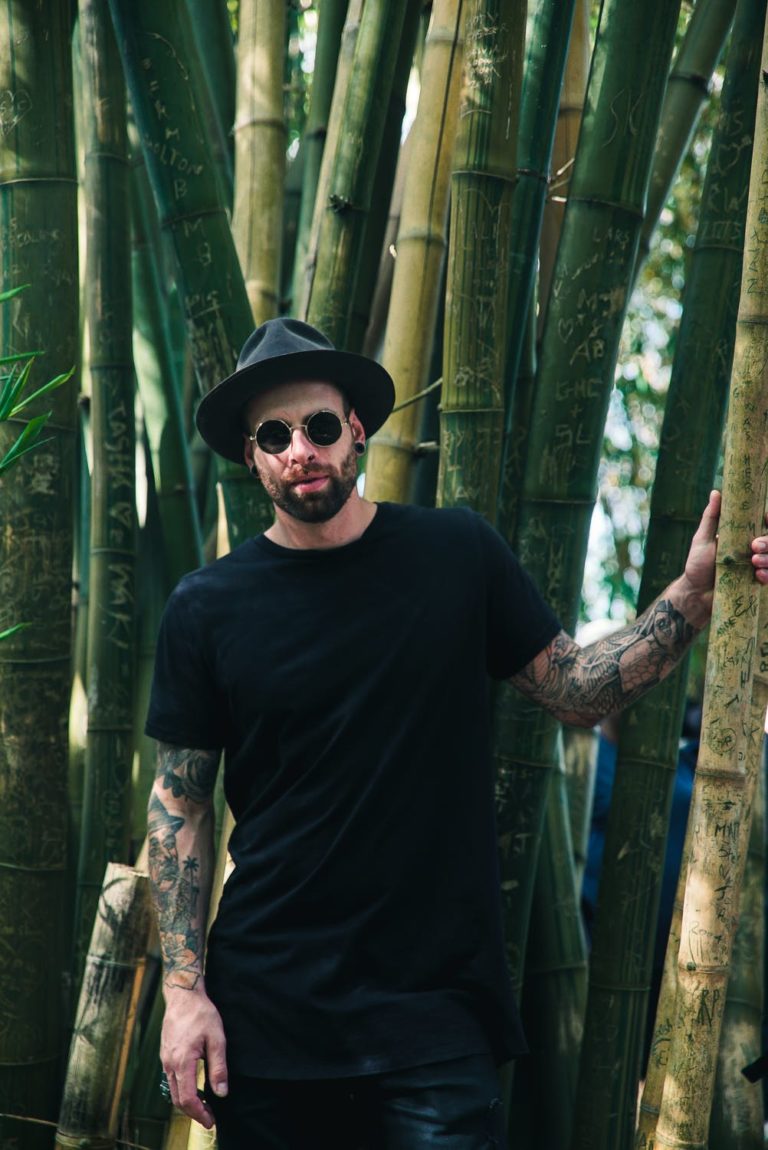 a person wearing a hat and sunglasses in a bamboo forest