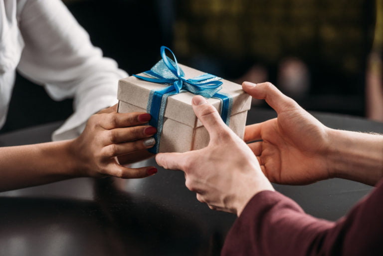 hands holding a small blue and white bag