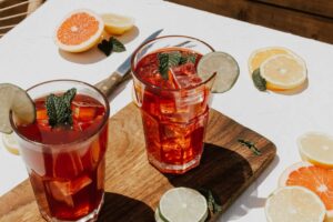 a table with glasses of liquid and sliced oranges